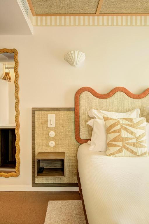 a bedroom with a bed with a mirror and a fireplace at Hôtel Gabriel in Menton