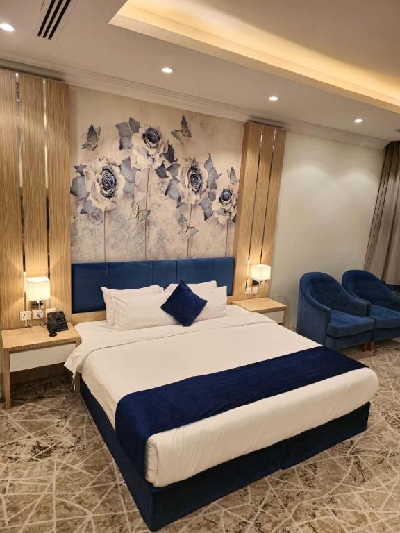 a bedroom with a large bed and blue chairs at Reef Home Hotel in Riyadh