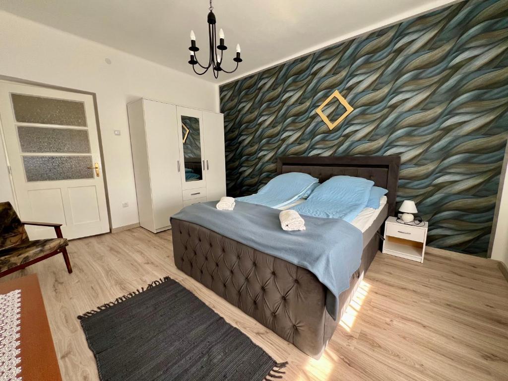 a bedroom with a large bed with a wave themed wall at AranyLak vendégház in Abádszalók