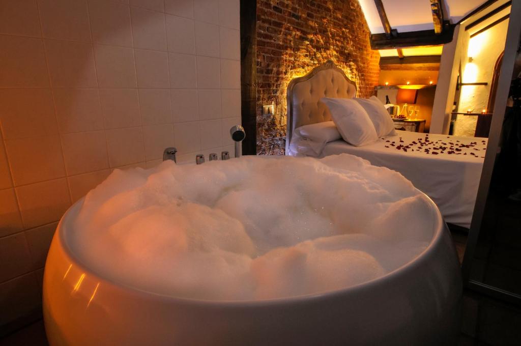 Hotel Rural La Viña - Only Adults في سان رافاييل: حوض استحمام مملوء بالرغوة في غرفة مع سريرين
