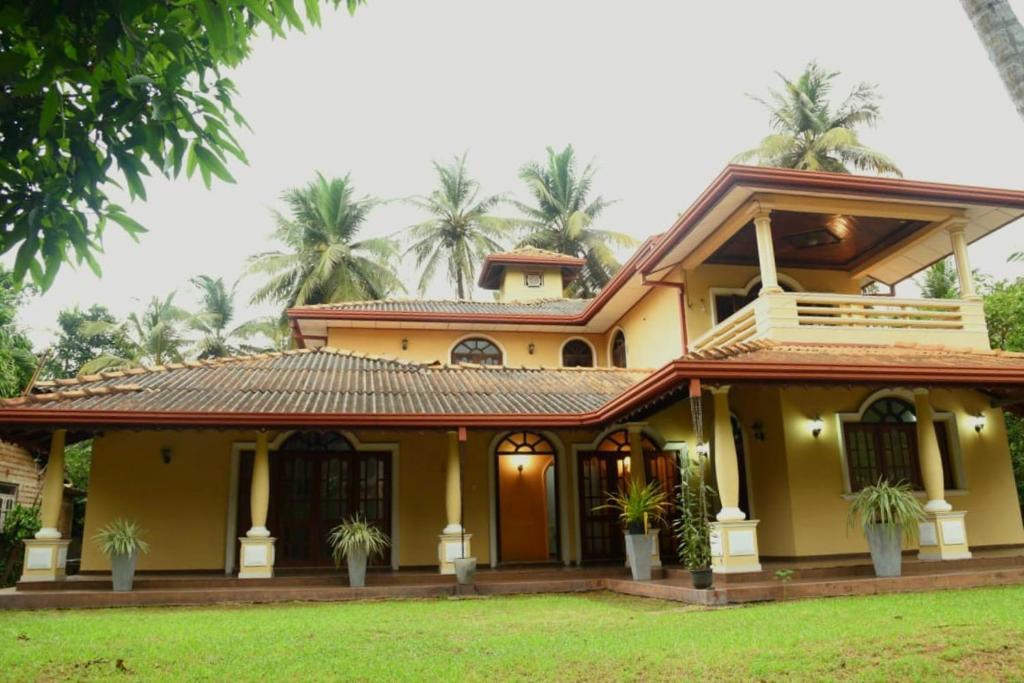 une grande maison jaune avec des palmiers en arrière-plan dans l'établissement Belvita Ayurveda Health Resort, à Negombo