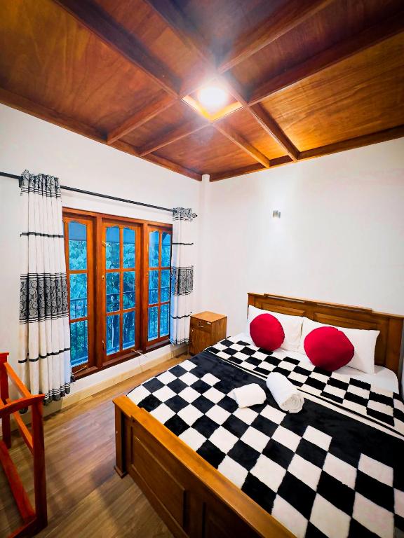 a bedroom with a checkered bed with red pillows at Niros Homestay Nuwara eliya in Nuwara Eliya