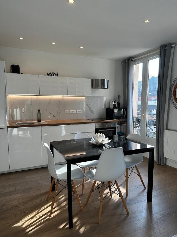 une cuisine avec une table noire et des chaises blanches dans l'établissement Charmant 2P lumineux aux portes de Paris, à Ivry-sur-Seine