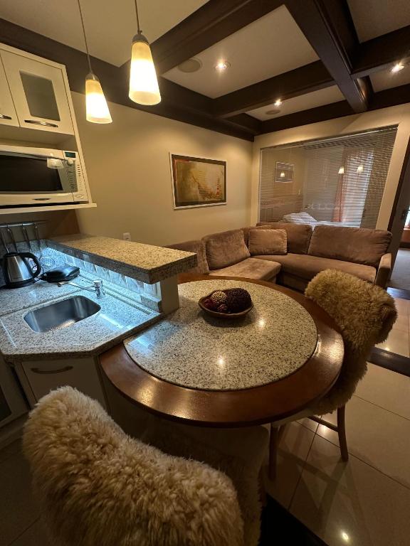 a kitchen and living room with a table and a couch at Flat Luxo 3010 com banheira Mountain Village Laje de Pedra Canela in Canela