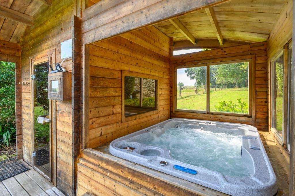 - un bain à remous dans une cabane en rondins dotée de fenêtres dans l'établissement Loft Atypique ancienne étable, à Cléguérec