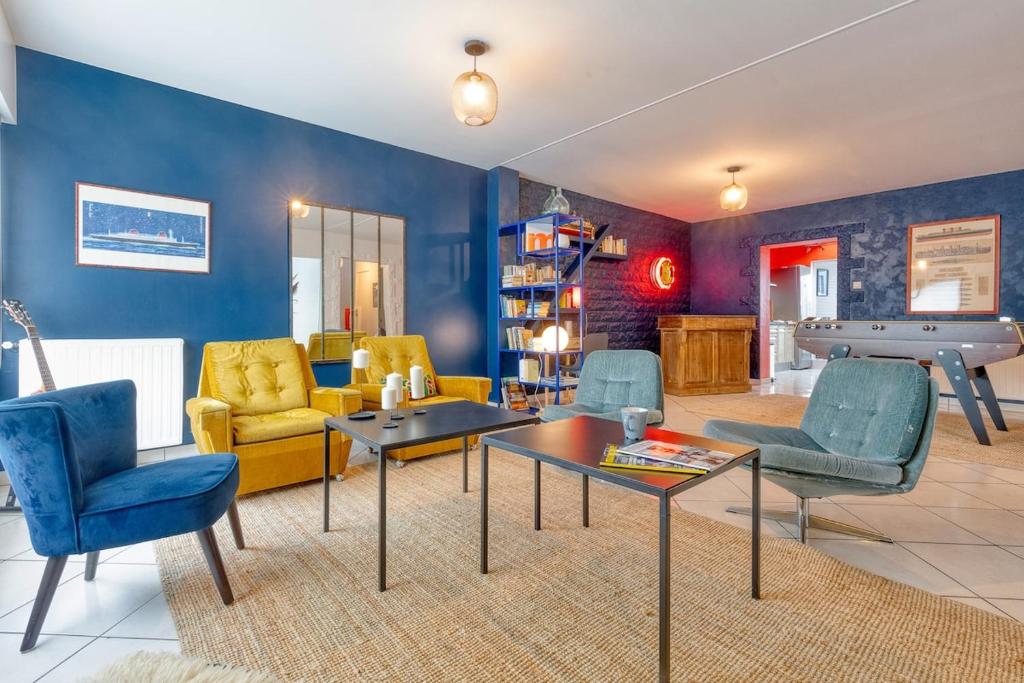 - un salon avec des murs bleus, une table et des chaises dans l'établissement L'Escale Maison Bleue proche chantiers atlantique, à Saint-Nazaire