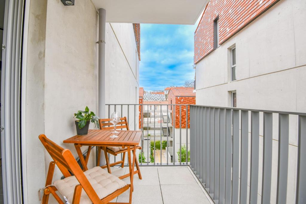 Cet appartement dispose d'un balcon avec une table et des chaises en bois. dans l'établissement Appart 1 ch avec balcon et parking à la Joliette, à Marseille
