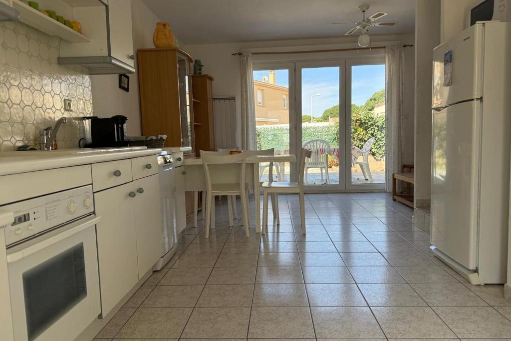 - une cuisine avec des appareils électroménagers blancs et une table avec vue dans l'établissement Maison 3 chambres à louer pour les vacances Grau du Roi, au Grau-du-Roi