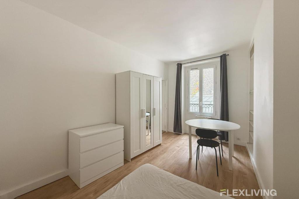 Cette chambre blanche dispose d'une table et d'un bureau. dans l'établissement Flexliving - One bedroom - 18ème, à Paris
