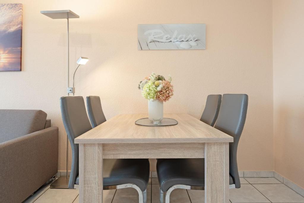 a dining room table with chairs and a vase with flowers at Haus Meeresgruß Relax in Grömitz