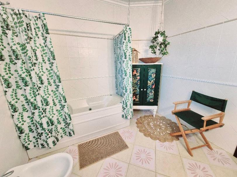 a bathroom with a tub and a chair and a shower curtain at Villa Alegria in Ericeira