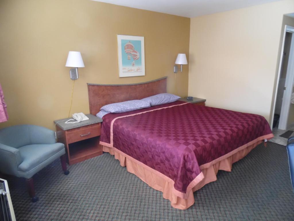 Habitación de hotel con cama y silla en Trails Motel, en Lone Pine