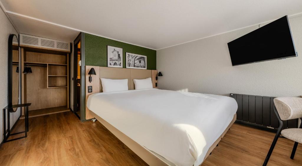 - une chambre avec un grand lit blanc et une télévision à écran plat dans l'établissement Campanile NATURE - Sannois Ermont, à Sannois