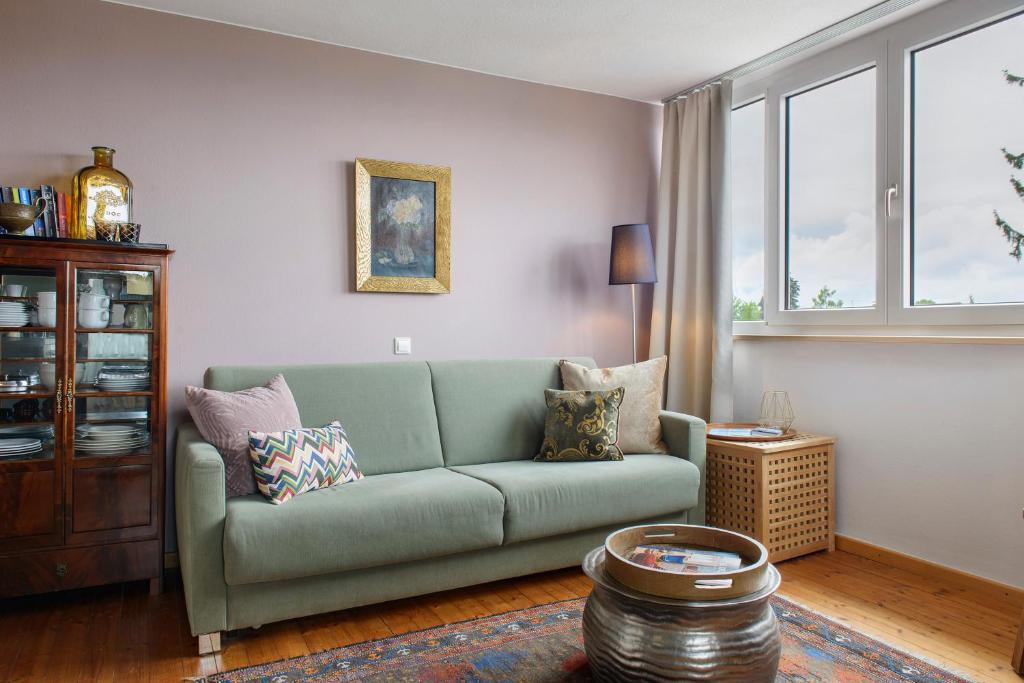 a living room with a green couch and windows at Gute Nacht in der Acht in Überlingen