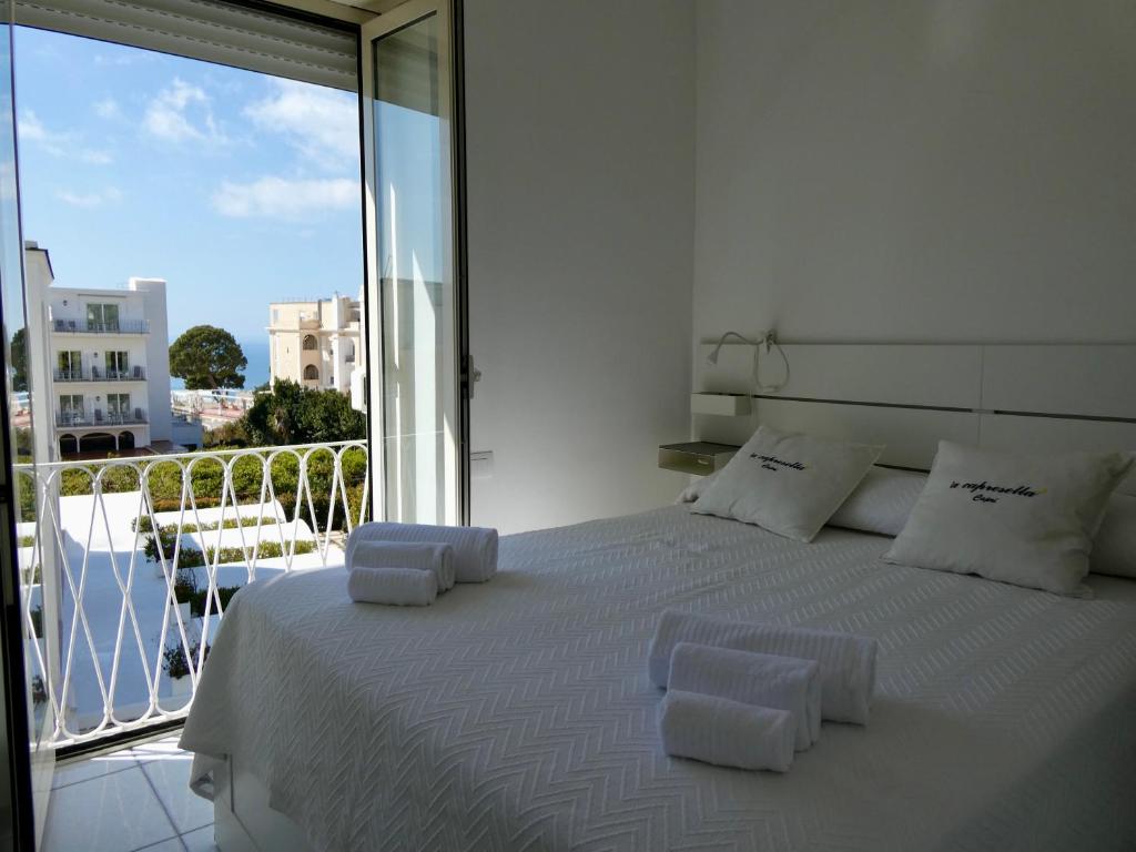 a bedroom with a white bed with a balcony at Capresella luxury apartment in Capri