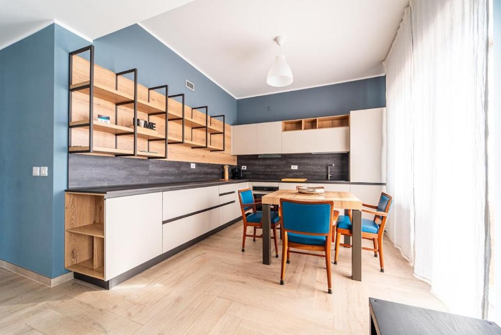 cocina con mesa de madera y sillas azules en Tiber Domus Fiumicino - Apt 6, en Fiumicino