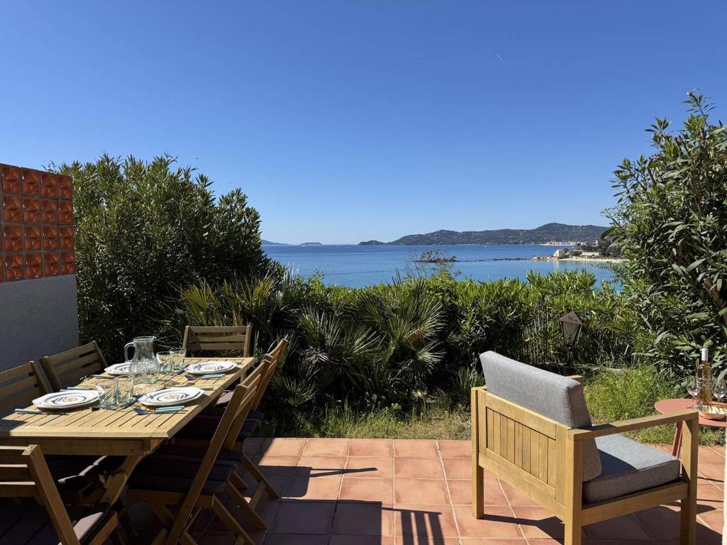 - une table en bois sur une terrasse avec vue sur l'eau dans l'établissement Les Floralies à Saint-Clair, au Lavandou