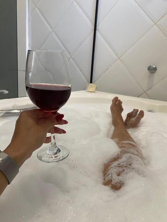 a person holding a glass of wine in a bath tub at Sitio Julimari in Itabirito