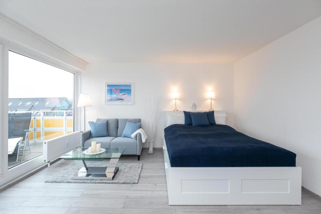 ein Schlafzimmer mit einem Bett, einer Couch und einem Tisch in der Unterkunft Strandhotel Scharbeutz Dünenliebe in Scharbeutz