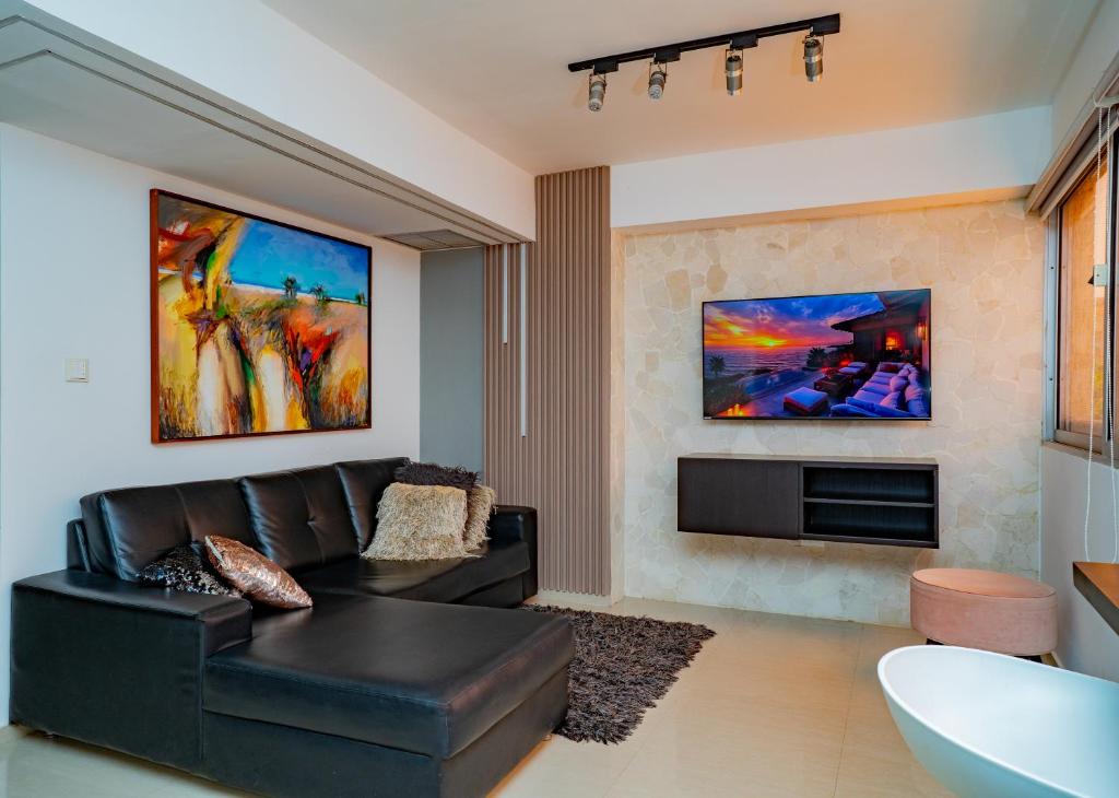 a living room with a black leather couch and a fireplace at Alojamiento Lecheria PV1 in El Morro de Barcelona