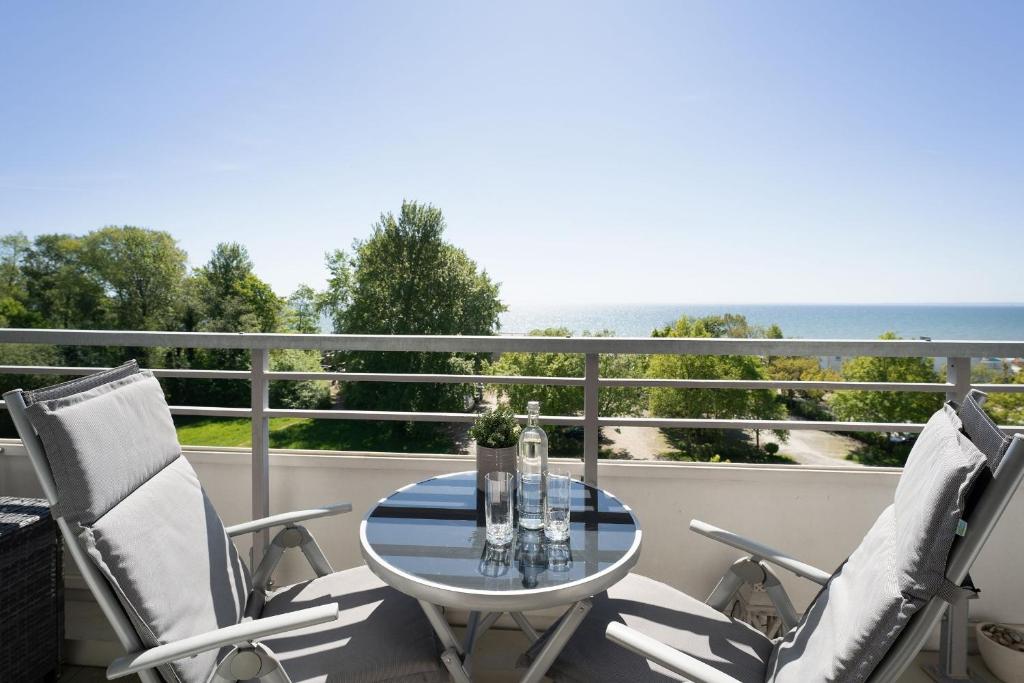 een tafel en 2 stoelen op een balkon met uitzicht op de oceaan bij Strandappartements am Leuchtturmweg Baltic-View in Kellenhusen