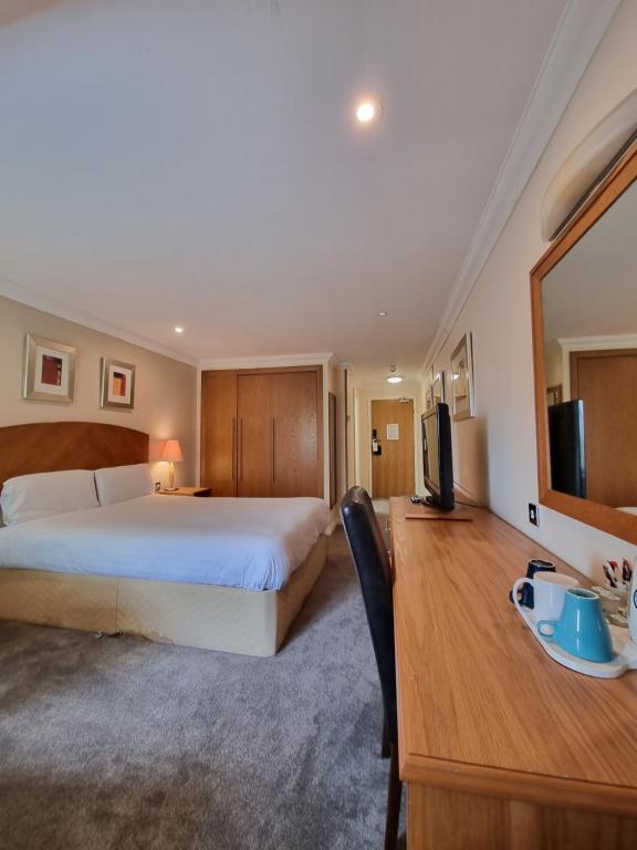 a bedroom with a bed and a desk and a television at Kegworth Hotel East Midlands Airport in Castle Donington