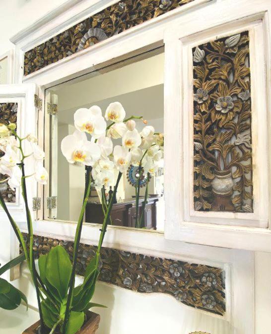 a vase with white flowers in front of a mirror at Hotel Sylesia in Letojanni