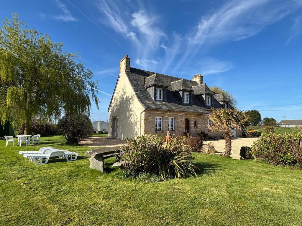 une grande maison en pierre sur un champ herbeux dans l'établissement Ti Breizh 8 pers 3km de la mer, à Guimaëc