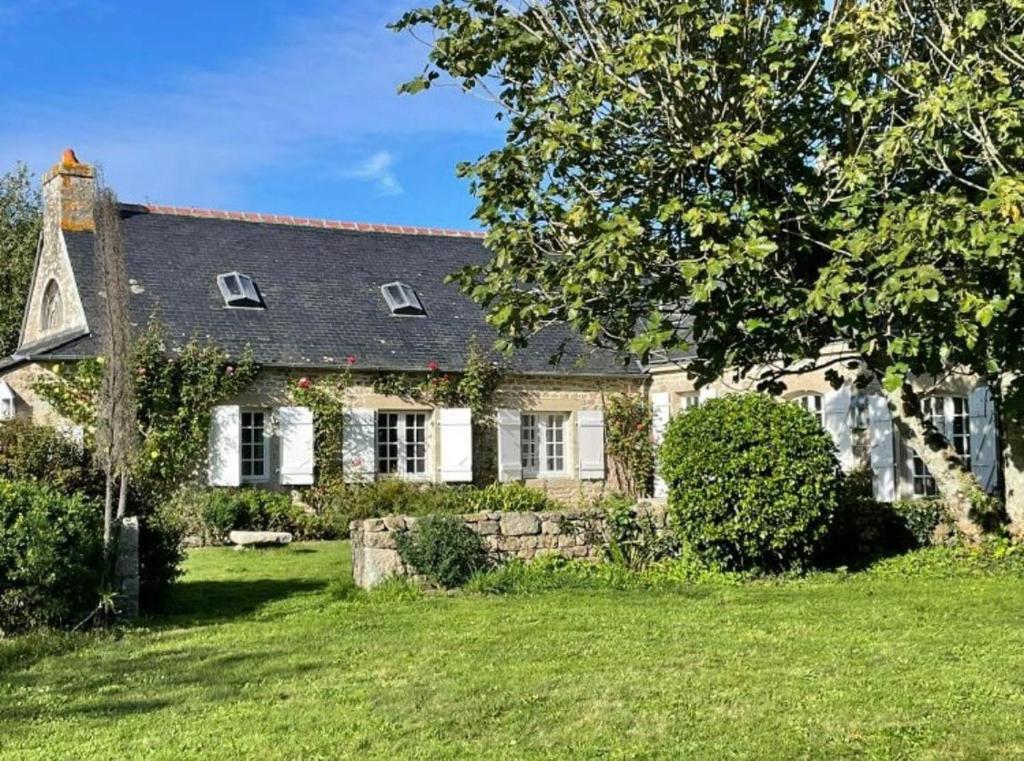 une grande maison blanche avec une cour gazonnée dans l'établissement Maison de Famille Pen Morvan, à Combrit