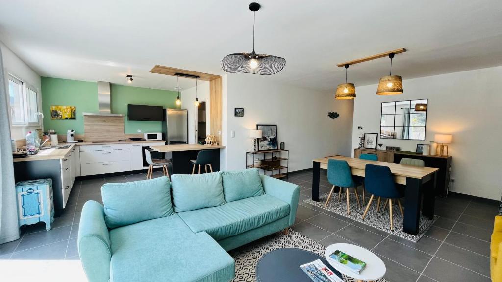 un salon avec un canapé bleu et une cuisine dans l'établissement Maison Océan, standing et plage, à Saint-Jean-de-Monts