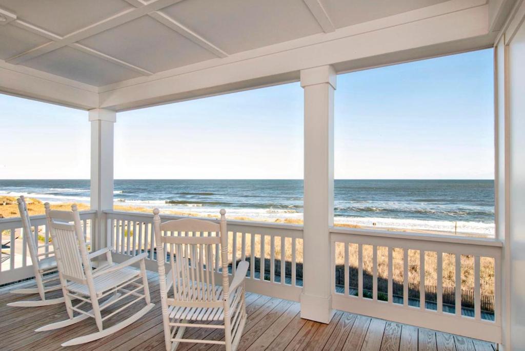 a porch with two chairs and a view of the ocean at Burpeau Unit A by Bryant Real Estate in Kure Beach