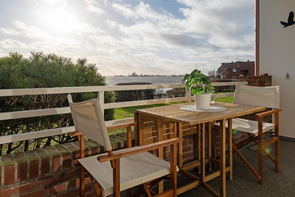 a wooden table and chairs on a balcony with a potted plant at Auszeit am Meer in Lemkenhafen auf Fehmarn