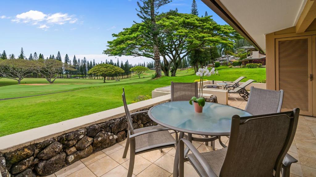 a patio with a table and chairs and a green yard at Kapalua Golf Villa 15P78 in Kapalua