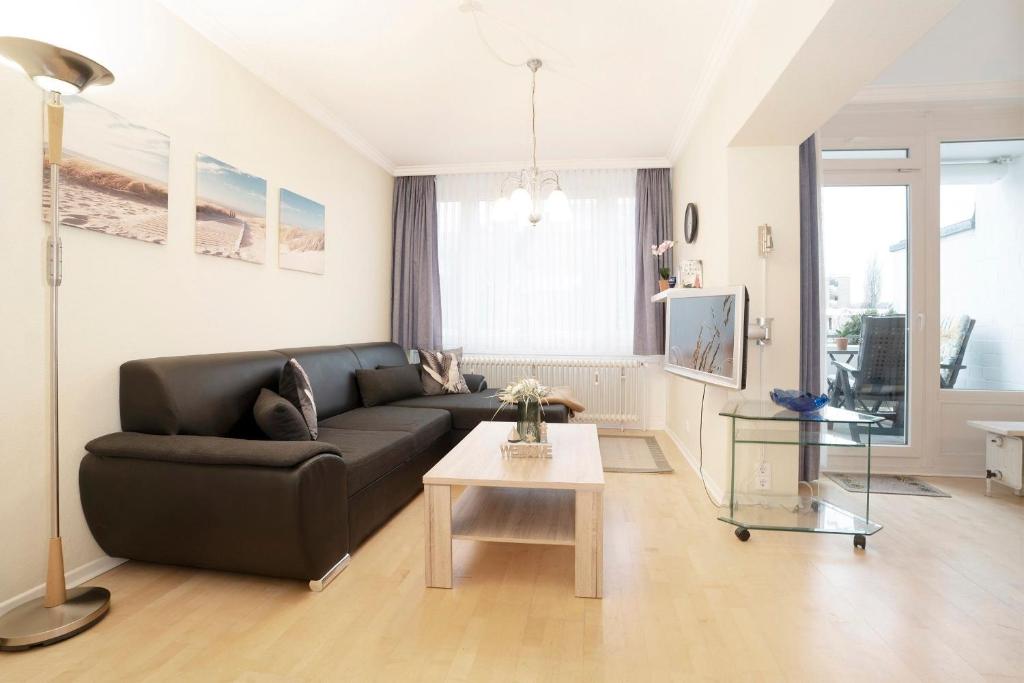 a living room with a black couch and a table at Tannenburg Wohnung 205 in Grömitz