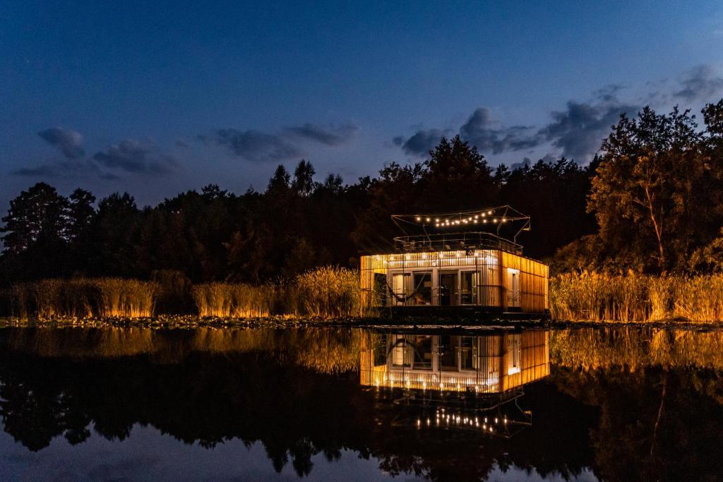 Nowawieś ZbąskaにあるWater Hideout - Floating Villas in Wild Natureの夜の湖畔のガラスの家