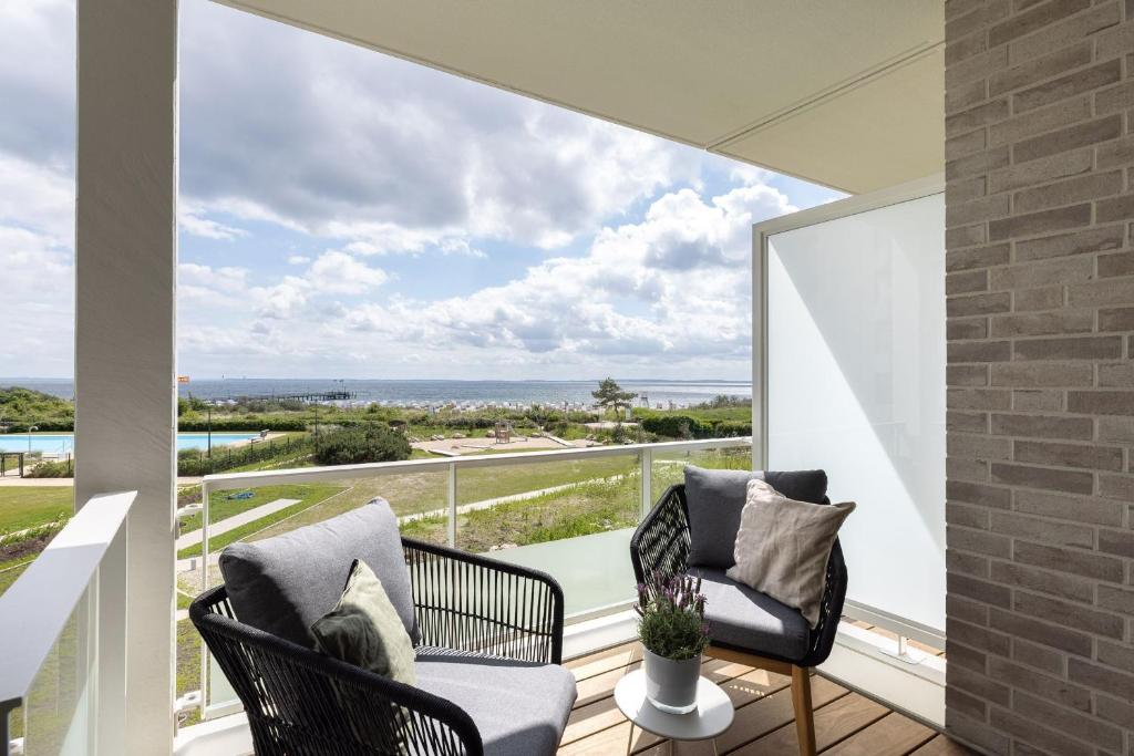a balcony with two chairs and a view of the ocean at Eichenhain Saltkrokan in Pelzerhaken