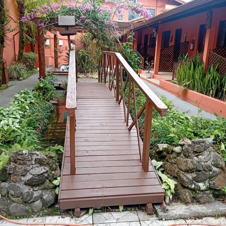 a wooden walkway in a garden with a building at Pousada Gaivotas do Guaraú in Peruíbe