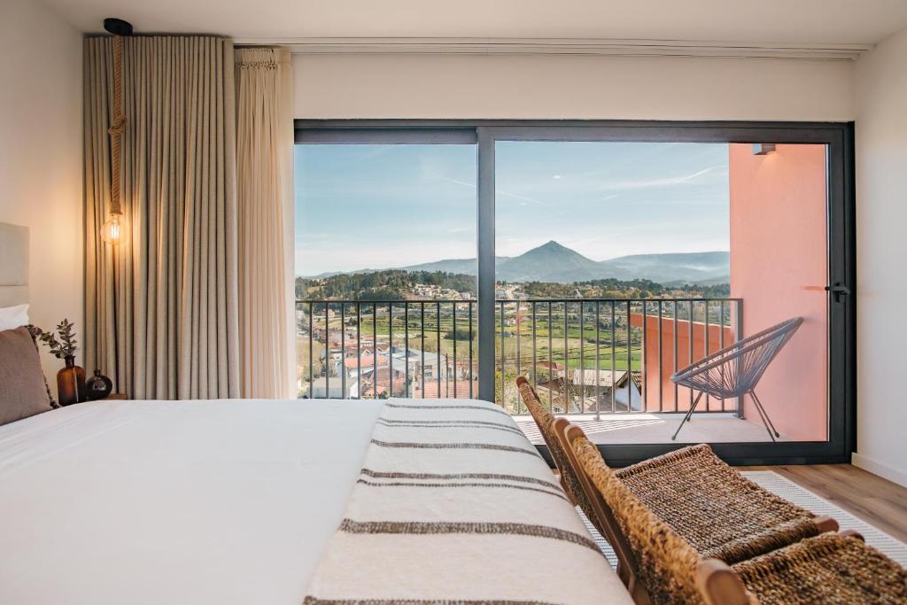 a bedroom with a bed and a balcony with a view at Villas Pinhão in Celorico de Basto