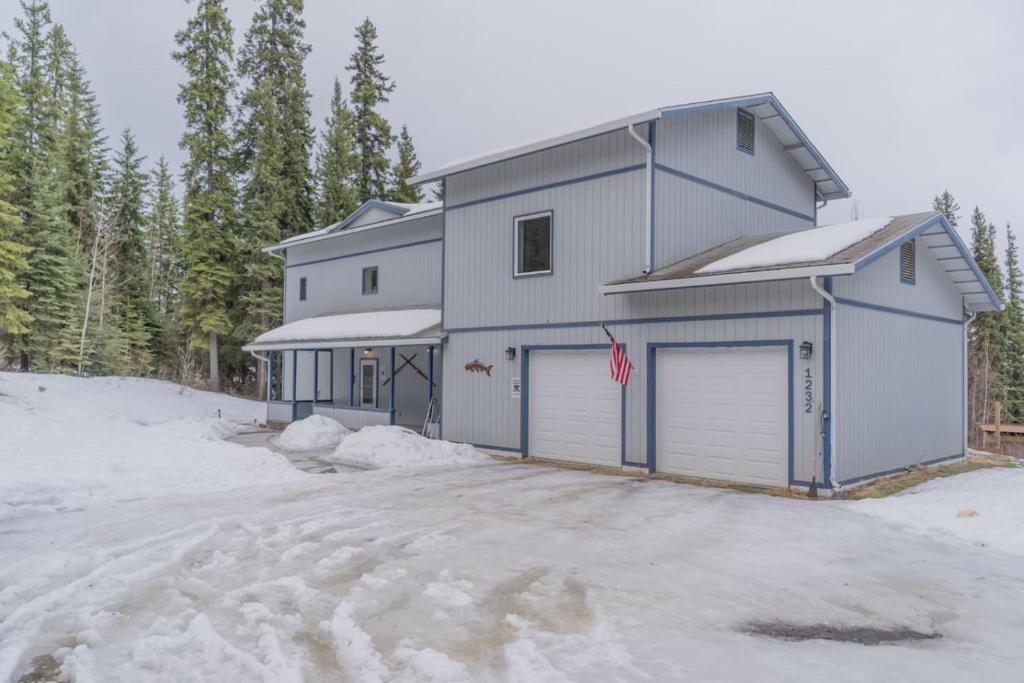 a house with two garage doors in the snow at The Chena Hills Chill And Hot Soak in Fairbanks