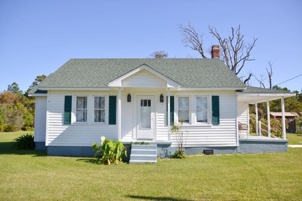 a small white house with a grass yard at 3BR Quiet Cottage Private Dock Fishing in Davis