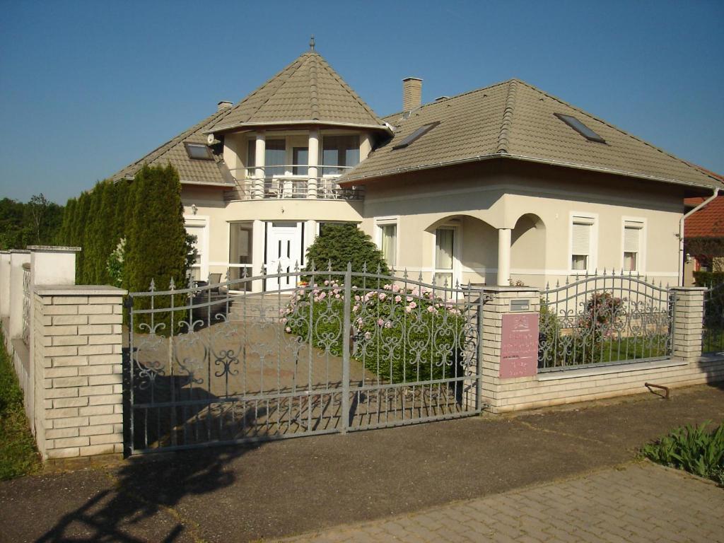 a white house with a gate in front of it at Fortuna Apartman in Bük