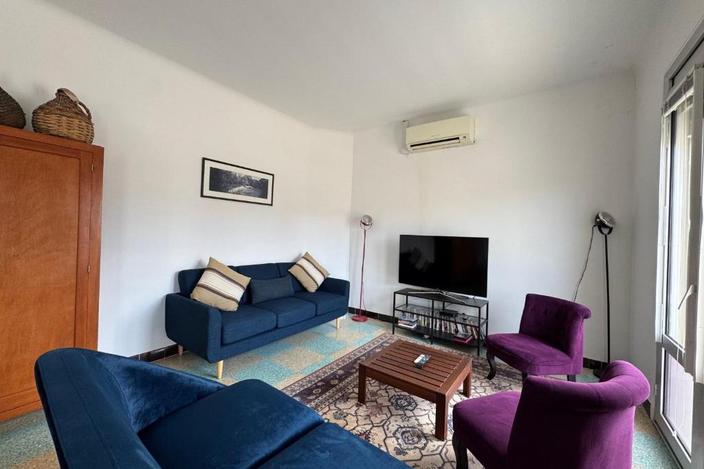 - un salon avec deux canapés bleus et une télévision dans l'établissement Place de l'Ancre Appartement 3 chambres avec garage 5 min plage & centre, au Grau-du-Roi