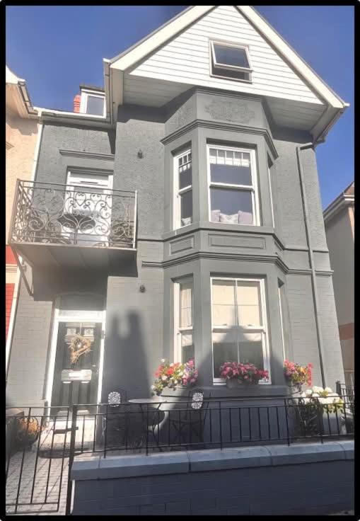 a large gray house with windows and a balcony at Coastal Cwtch in Moffat