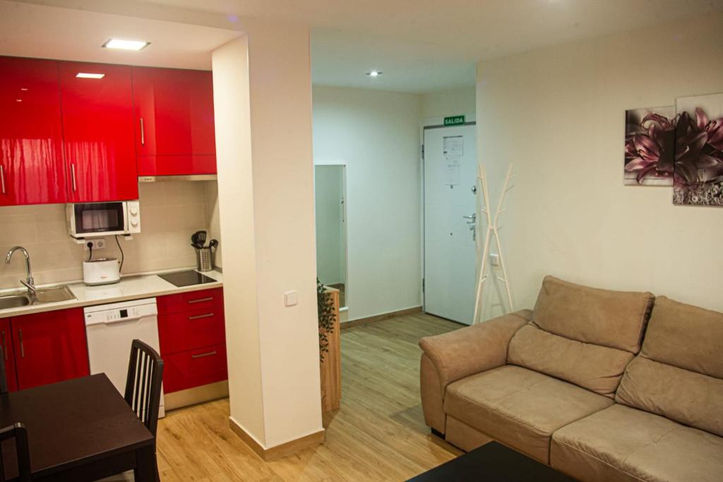 sala de estar con sofá y cocina con armarios rojos. en Centro Histórico Parking con NRU y licencia turística VT-13960, en Alcalá de Henares