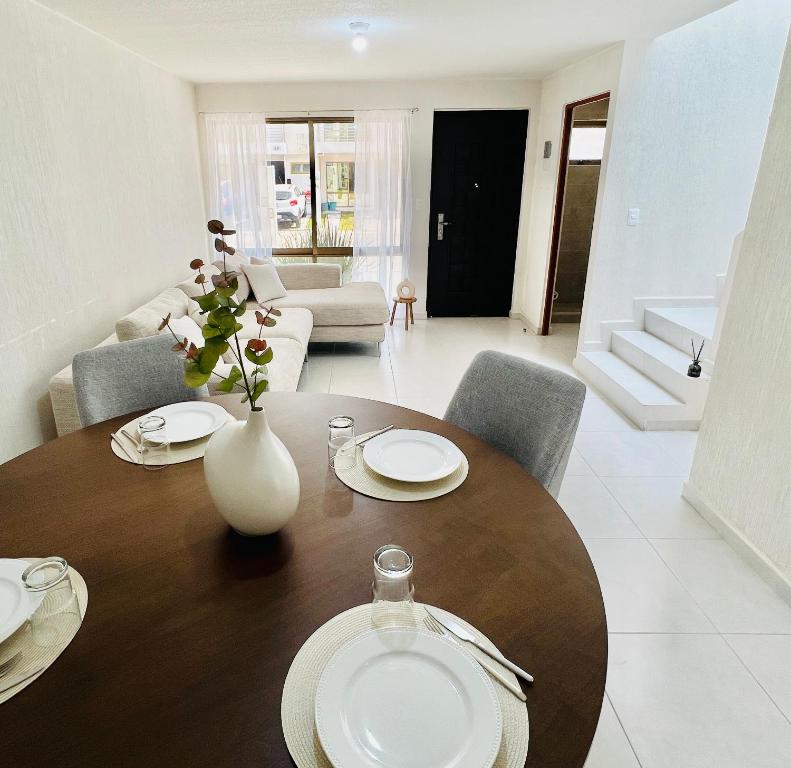 Una mesa de comedor con un jarrón de flores encima. en Casa lujosa con 3 baños y alberca, a min AIFA, en Tizayuca