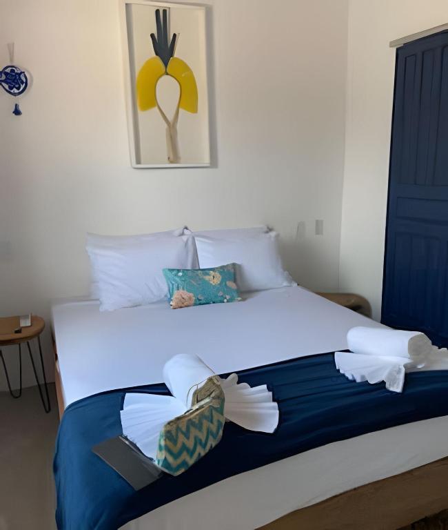 a bed with blue and white sheets and pillows at Casa aconchegante com piscina na praia da Barrinha in Barrinha