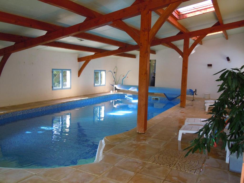a swimming pool in a house with a wooden ceiling at Cabane Perchée Spa Dordogne La Ferme de Sirguet in Monsac