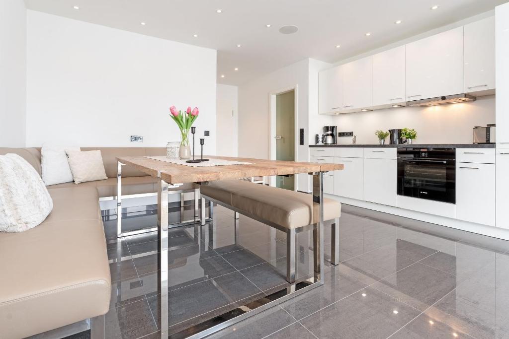 a kitchen with white cabinets and a wooden table and chairs at Strandvilla Augustusbad Meerverliebt in Scharbeutz