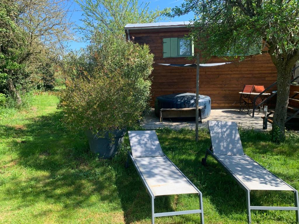 two benches in the grass in front of a cabin at La roulotte de Plajoulet in Mirepoix