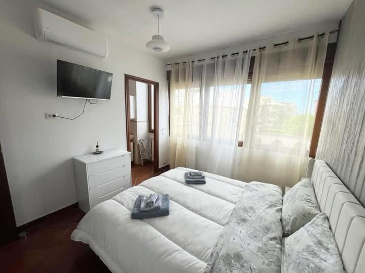 Un dormitorio con una gran cama blanca y un televisor. en Karol Beach House, en Santa Marinella